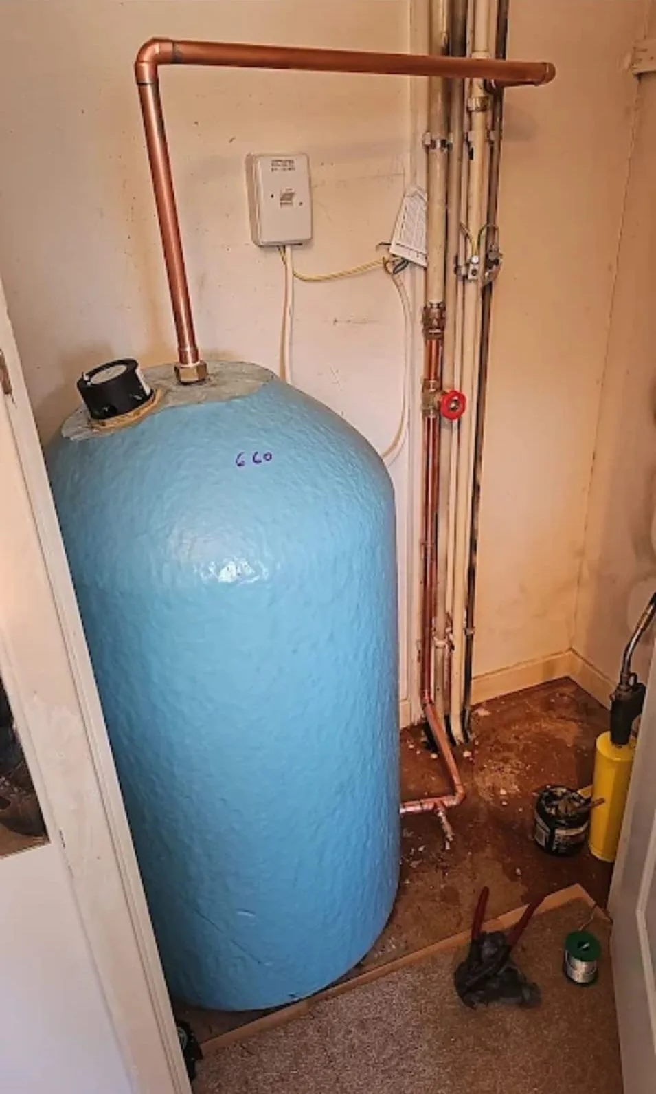 Hot-water cylinder installation with copper pipework and safety devices in an airing cupboard