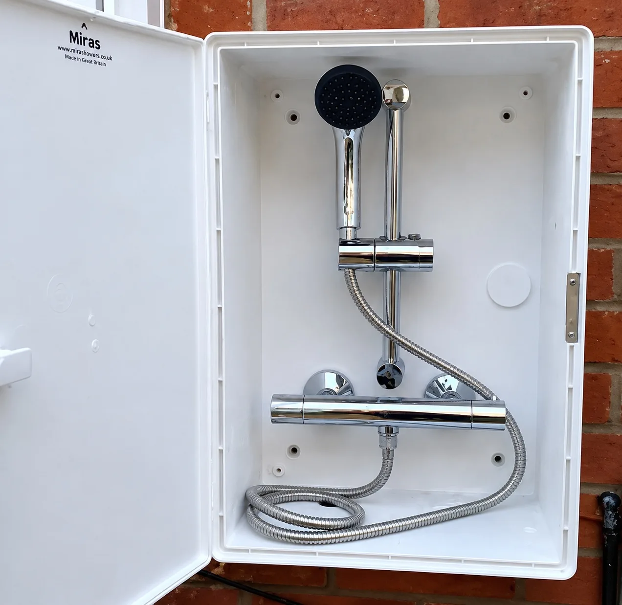 Wall-mounted thermostatic shower valve and handset installed in a weatherproof enclosure for a dog-washing station