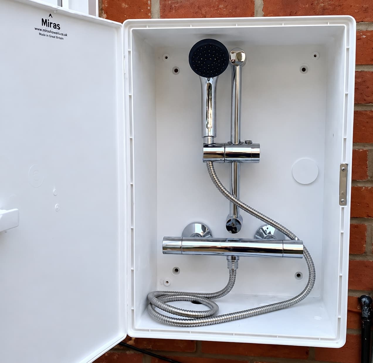 Wall-mounted thermostatic shower valve and handset installed in a weatherproof enclosure for a dog-washing station